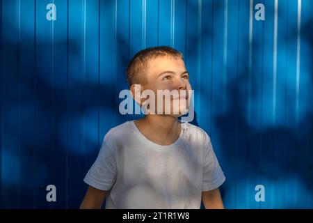 Dreams on the Horizon: A Boy's Hopeful Gaze Against the Blue Wall Stock Photo
