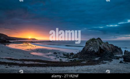 Absolutely stunning sunrise landscape image of Kennack Sands in Cornwall UK wuth dramatic moody clouds and vibrant sunburst Stock Photo