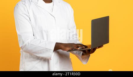 Unrecognizable African American Man Doctor Using Laptop On Blue Background Stock Photo
