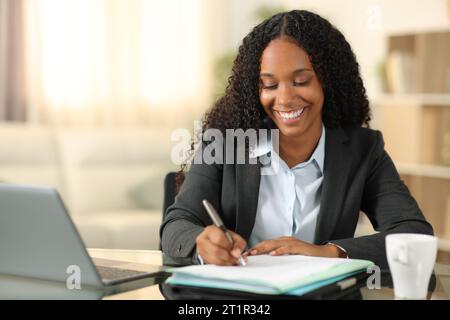 Happy black tele worker filling form working at home Stock Photo