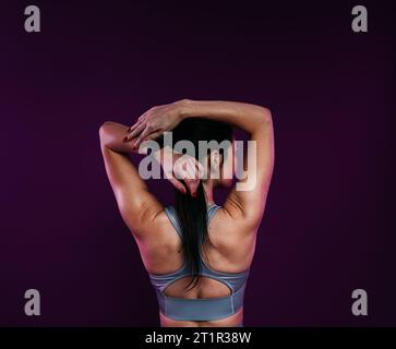 Back view of a young athlete stretching her arms before workout Stock Photo