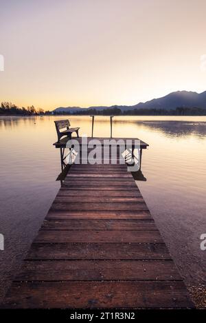 A wooden footbridge on the shore of Lake Kochel in the golden light of dawn in autumn, Bavaria, Germany Stock Photo