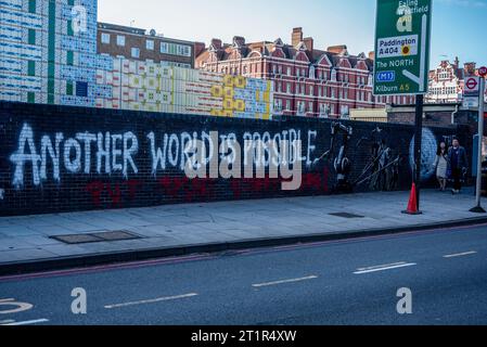 London, UK. 14th Oct, 2023. A couple walks by the potential new Banksy's mural in London. A potential new Banksy's mural appeared on Monday in London near the Edgware Road underground station. The artwork shows three figures pulling away a giant robot arm accompanied by the words: 'Another world is possible. Put paint everywhere!'. Credit: SOPA Images Limited/Alamy Live News Stock Photo