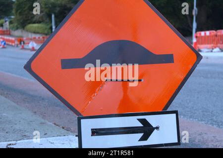 A photo of an orange speed bump road sign beside a road in Dublin, Ireland. Stock Photo