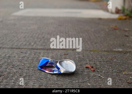 A photo of a crushed up, littered energy drink can on the path. Stock Photo