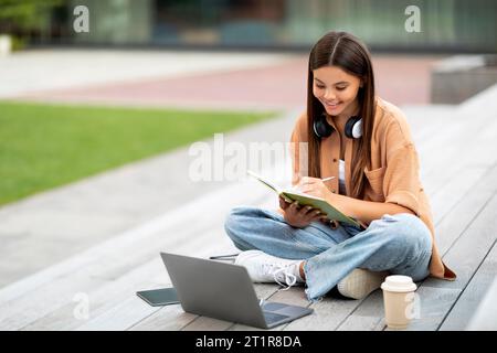 Content student using laptop outdoor, solitude university setting Stock Photo