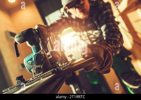 Caucasian Construction Contractor Worker Cutting Plywood Using Battery Operated Cordless Circular Saw. Modern Construction Equipment Theme. Stock Photo