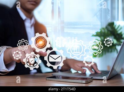 Businesswoman pointing at gears and icons. Operations management. Setting business goals, communication, workflow, problem solving, high performance, Stock Photo