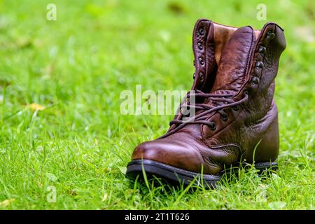 A brown lost or discarded leather boot on green grass. Stock Photo