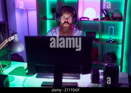 Young redhead man streamer playing video game using computer at gaming room Stock Photo