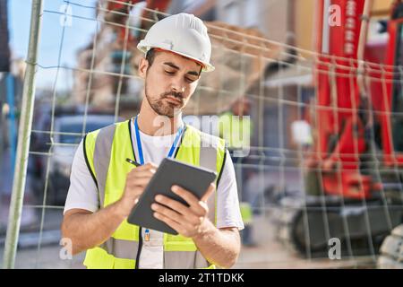 Young hispanic man architect drawing on touchpad at street Stock Photo