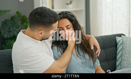 Man and woman couple sitting on sofa consoling girlfriend at home Stock Photo