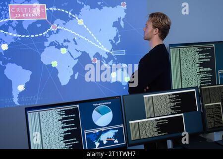 Back View in the Cyber Security Control Center Operator Working. Multiple Screens Showing Technical Data and Alerts. Stock Photo