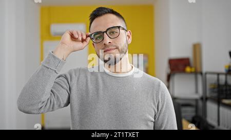 Hispanic man business worker with serious face holding glasses at office Stock Photo