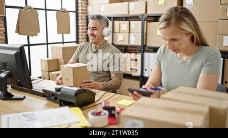 Man and woman ecommerce business worker having video call holding package working at office Stock Photo