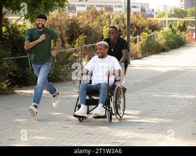 Three diverse male friends one of them in a wheelchair having fun in a city Stock Photo