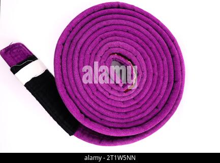 A rolled up brazilian jiu jitsu ranking belt purple with four stripes Stock Photo