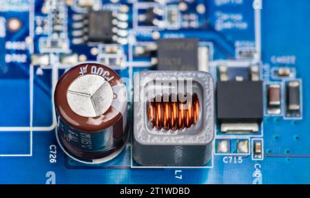 Closeup of electronic components on printed circuit board of power supply. Brown electrolytic capacitor, inductor in gray housing or black transistors. Stock Photo