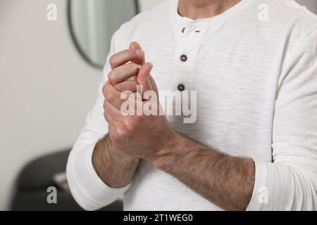 Man cracking his knuckles on blurred background, closeup. Bad habit Stock Photo