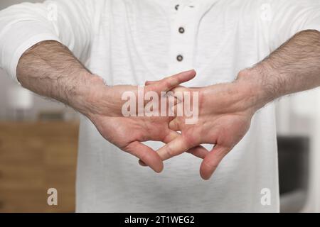 Man cracking his knuckles on blurred background, closeup. Bad habit Stock Photo