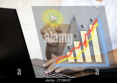 A woman's hand presses a virtual button on a graph with a histogram while working on a laptop at the table, business and reports, statistics Stock Photo