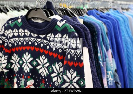 Knitted sweaters with winter pattern in a store. Traditional warm outfit for New Year holidays Stock Photo