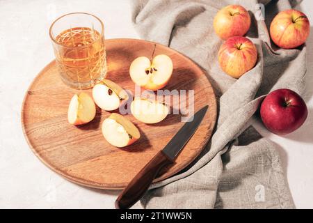 Fresh ripe apples and apple juice in a glass on wooden tray with grey napkin on white table. Autumn harvest, Thanksgiving concept. Top view. Stock Photo