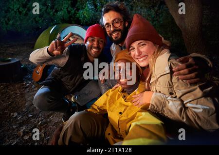 Group of cheerful multi-ethnic friends pose hugging and smiling for outdoor selfie phone. Vacations. Stock Photo