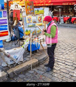 Painter and display of the artist's works of colourful paintings of flowers for sale, Place du Tertre, Montmartre, 18th arrondissement, Paris, France Stock Photo