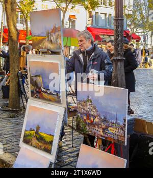 A male artist at work painting a picture on canvas on an easel outdoors  in Place du Tertre, Montmartre, 18th arrondissement, Paris, France Stock Photo