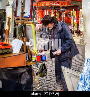 A male artist at work painting a picture on canvas on an easel outdoors  in Place du Tertre, Montmartre, 18th arrondissement, Paris, France Stock Photo