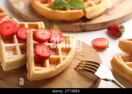 Tasty Belgian waffles with strawberries, mint and fork on white table, closeup Stock Photo