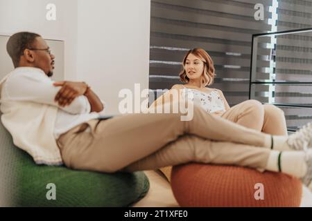 Multiracial employees taking a break from work. Diverse coworkers lying on lazy bags at the office, taking a break. Stock Photo