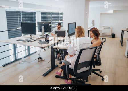 Confident, diverse business team in creative office. Analyzing reports, planning, using technology. Successful start-up team. Stock Photo