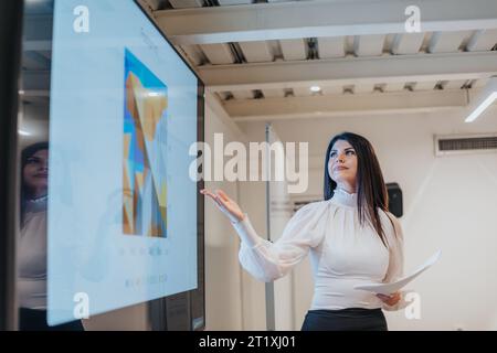 Female businesswoman presenting on a TV set in front of her colleagues Stock Photo