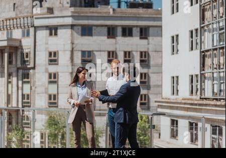 Young construction engineers discussing project while standing on a construction site in the city Stock Photo