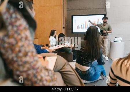 Handsome male employee explaining profit growth to his colleagues at modern meeting room Stock Photo