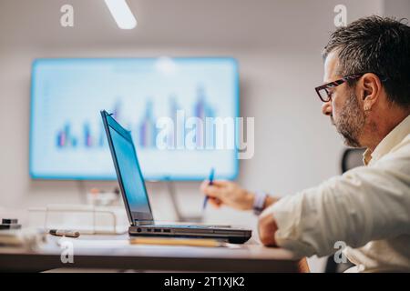 Diverse professionals discuss architectural blueprints in an office meeting. Multinational team focuses on collaboration and success. Stock Photo