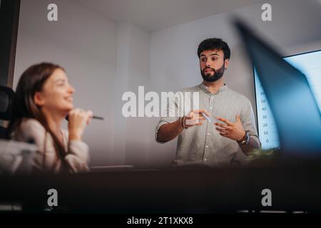Collaborative Business Meeting in Conference Room with Architects and Executives Discussing Architectural Blueprints and Graph Charts Stock Photo