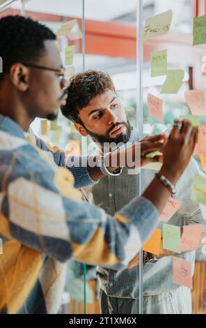 Creative Collaboration in a Diverse Workplace: Sharing Knowledge and Writing Ideas on Glass Wall Stock Photo