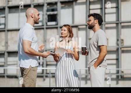 Small group of architects, engineers, and designers analyzing a blueprint outdoors to create a modern building design. Stock Photo