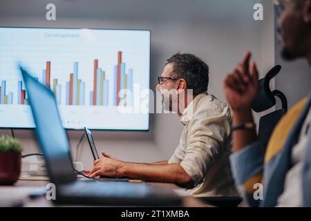Multiracial Business Team Collaborating on Architectural Plans in Conference Room Stock Photo