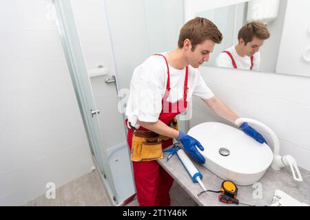 a worker installs a wash basin in a bathroom. Stock Photo