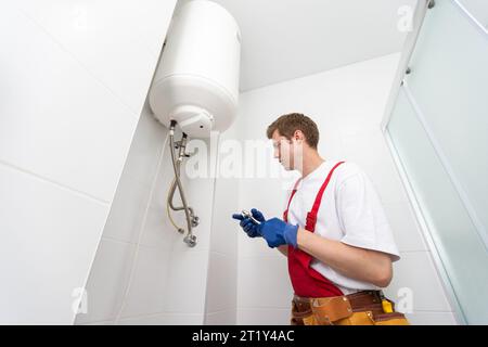 Closeup of plumber using screwdriver while fixing boiler or water heater, working on heating system in apartment Stock Photo