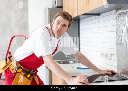 craftsman installs hob in kitchen. Household Appliance Installation Services Concept. Stock Photo