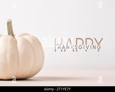 Happy Thanksgiving message with white colored Autumn pumpkin on wooden table against white background. Greeting card template. Stock Photo