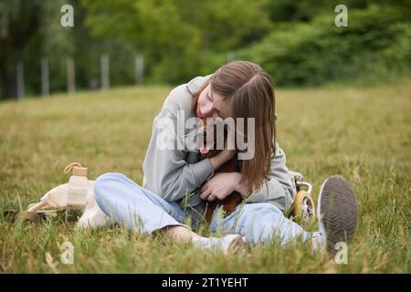 Dog lover girl hugging a dachshund in a wheelchair. Loving pet owner concept Stock Photo