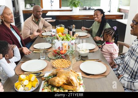 Happy african american multi generation family talking at thanksgiving dinner Stock Photo