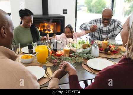 Happy african american multi generation family holding hands at thanksgiving dinner Stock Photo