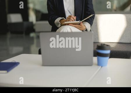 Close up of business woman is making notes during work on laptop in office Stock Photo